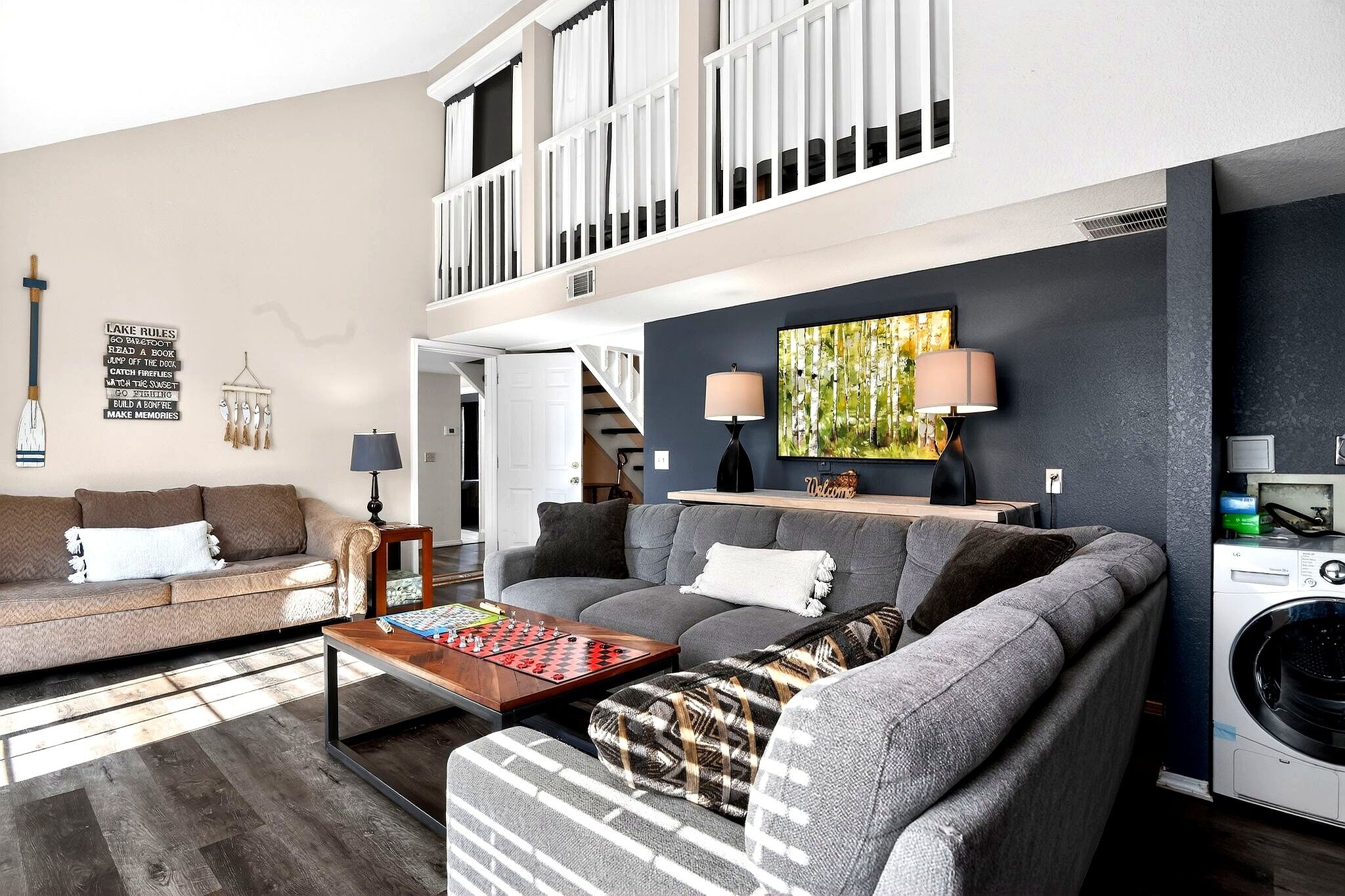 A living room with a sofa, a coffee table, a washing machine, and a painting on the wall.