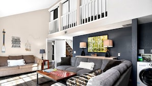 A living room with a sofa, a coffee table, a washing machine, and a painting on the wall. - Lake Views•Near SDC•Game Nights•2 Decks•King Bed•Marina Access•Resort Amenities! (Branson)