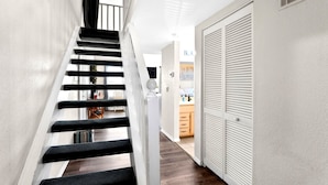 A staircase with black steps and white walls, leading to a kitchen area with wooden cabinets and a countertop. - Lake Views•Near SDC•Game Nights•2 Decks•King Bed•Marina Access•Resort Amenities! (Branson)