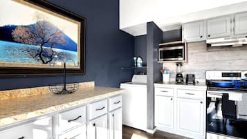 A modern kitchen with white cabinets, a granite countertop, a stainless steel oven, and a microwave.