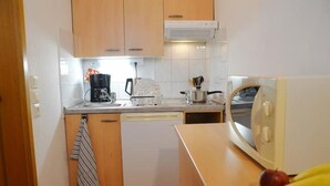 Una cucina compatta con mobili in legno, lavastoviglie, macchina del caffè e microonde.