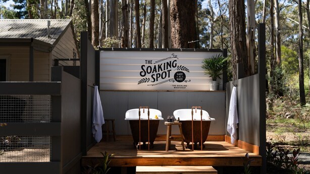 A wooden deck with two tubs, a sign reading 'The Soaking Spot,' and a view of a forest. - The Duckling quintessential bush retreat set amongst towering gums. One bedroom - dog friendly (Wheatsheaf)