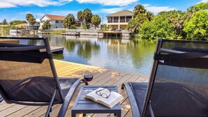 A wooden deck with two chairs, a table, a glass of red wine, and an open book. - Kayaks/LocatedonCanal/Sunsets/HeatedPool (Hernando Beach)