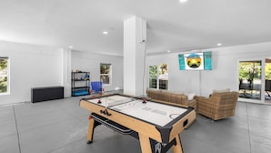 A spacious indoor area with a foosball table, a sofa, and a wall-mounted TV. - Kayaks/LocatedonCanal/Sunsets/HeatedPool (Hernando Beach)