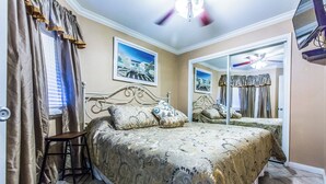 A bedroom with a bed, a mirror, and a window with curtains.