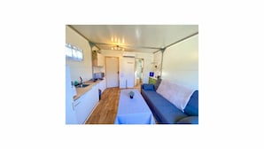 A compact living space with a kitchenette, a sofa, and a small table.