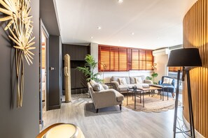 A modern living room with a sectional sofa, a coffee table, and a lamp. - Grazia - Vue mer, piscine, centre ville (Biarritz)