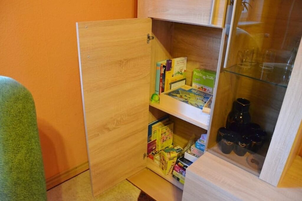 Un espacio de almacenamiento compacto con estantes que contienen libros, una caja verde y recipientes negros.
