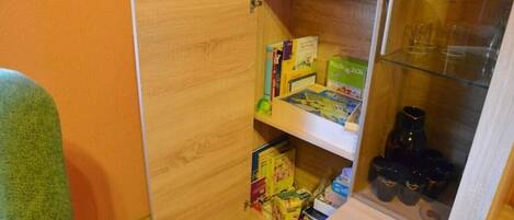 Un espacio de almacenamiento compacto con estantes que contienen libros, una caja verde y recipientes negros.