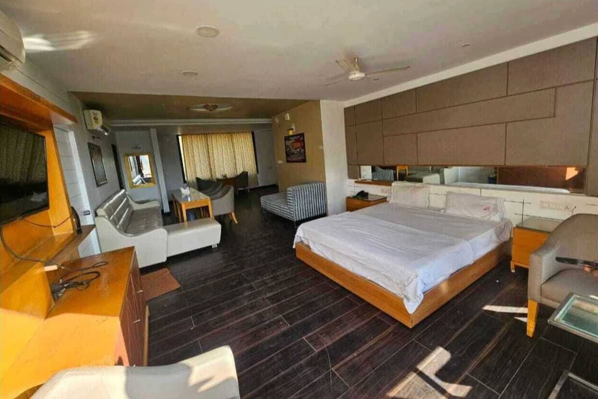 Une chambre d’hôtel avec un grand lit, un bureau, une chaise, un canapé et un téléviseur.