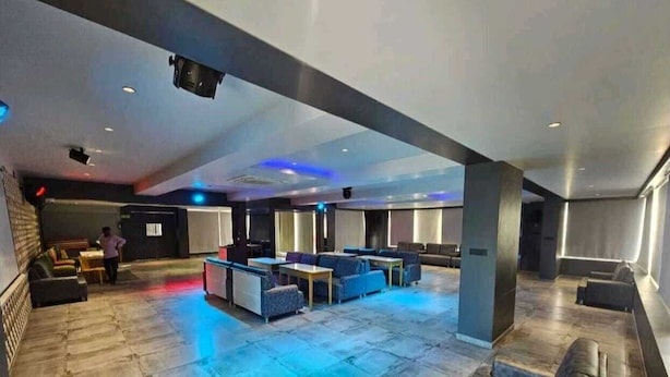 En rymlig entréhall med högt i tak, en sittgrupp med soffor och bord, och en person som går förbi i bakgrunden.