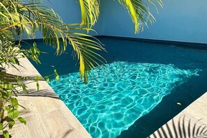 A clear blue pool surrounded by tiled flooring and palm trees. - Tamarindo Condo | Pool, Parking & Sunset Views (Tamarindo)