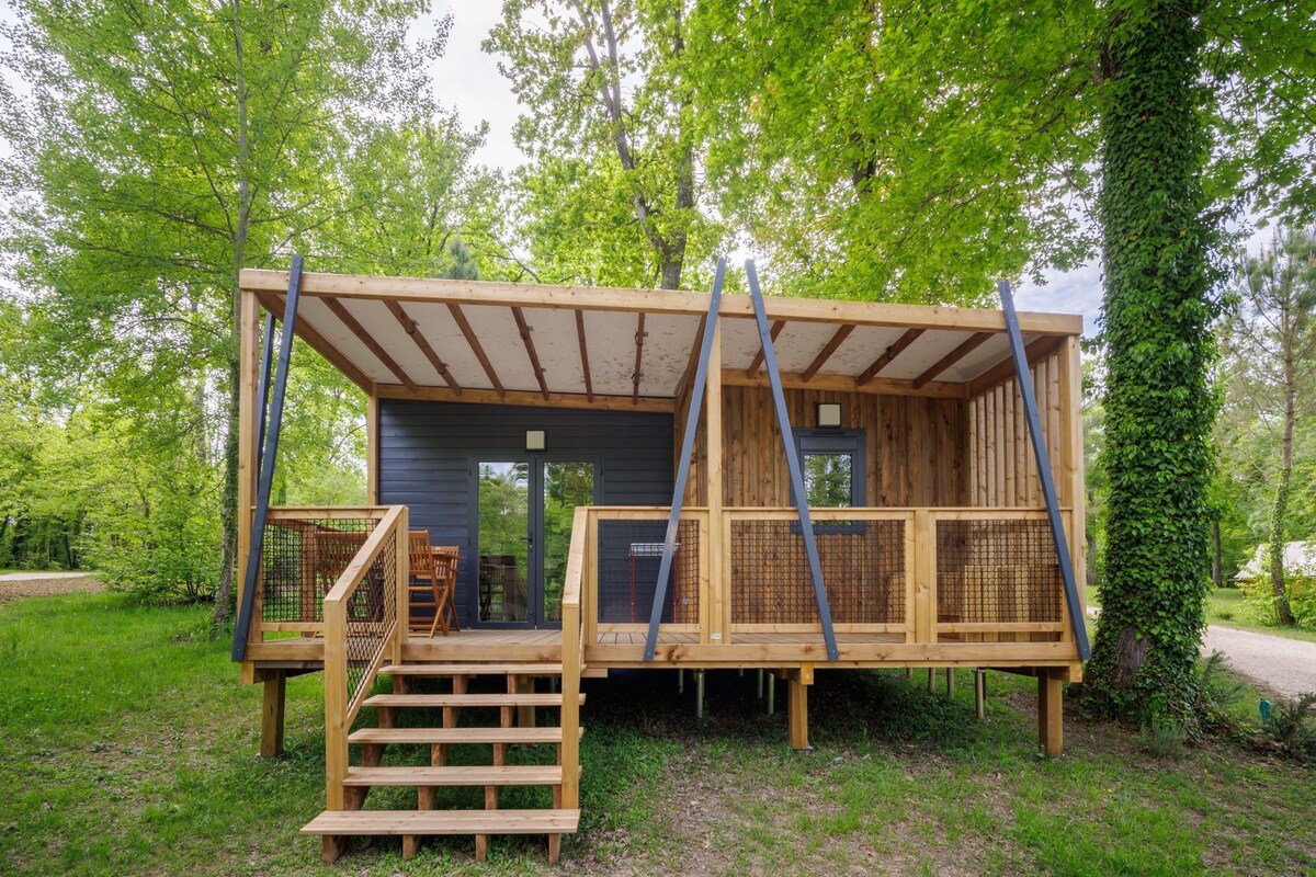 Una pequeña cabaña de madera con un porche, una escalera y una puerta de acceso al interior.