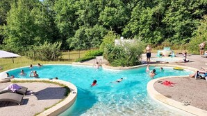 Une piscine dotée de plusieurs couloirs, entourée d’une terrasse en pierre et de chaises longues.