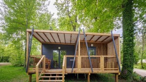 Une cabane en bois dotée d’un balcon, d’un escalier et d’une porte donnant accès à un espace intérieur.