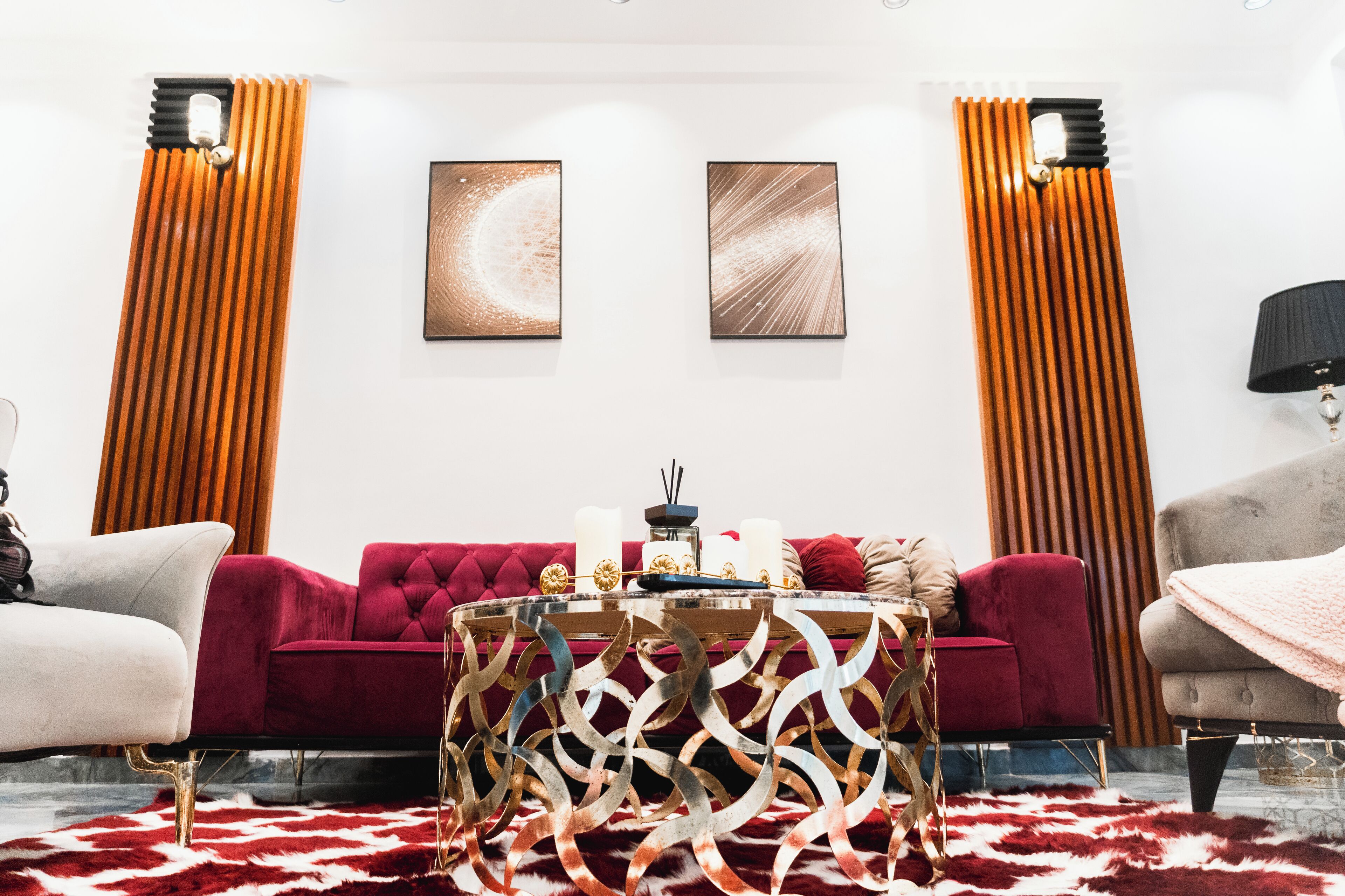 Een moderne woonkamer met een rode bank, een ronde salontafel en een vloerkleed met een patroon.