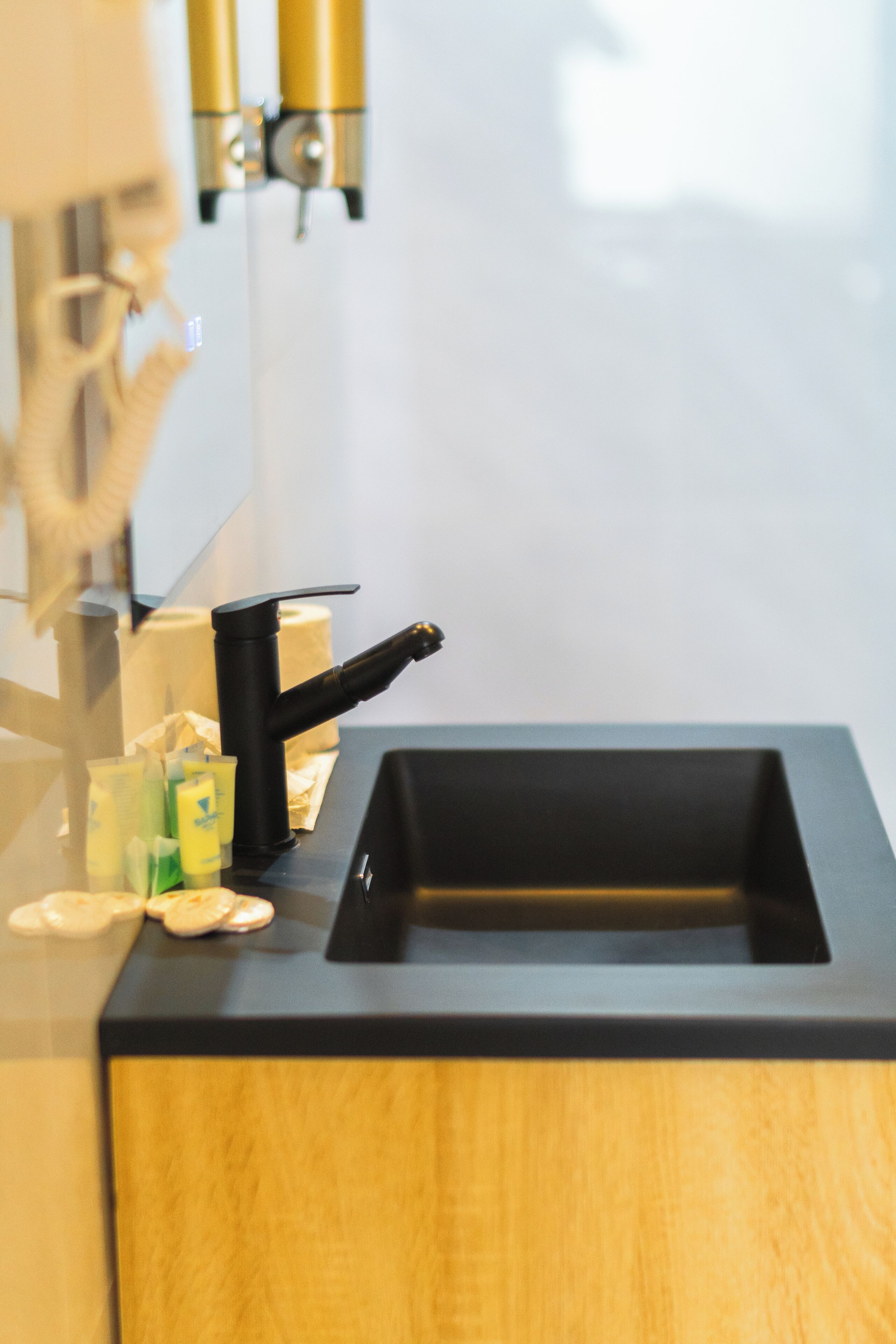 A bathroom with a black sink, a mirror, and a towel dispenser.