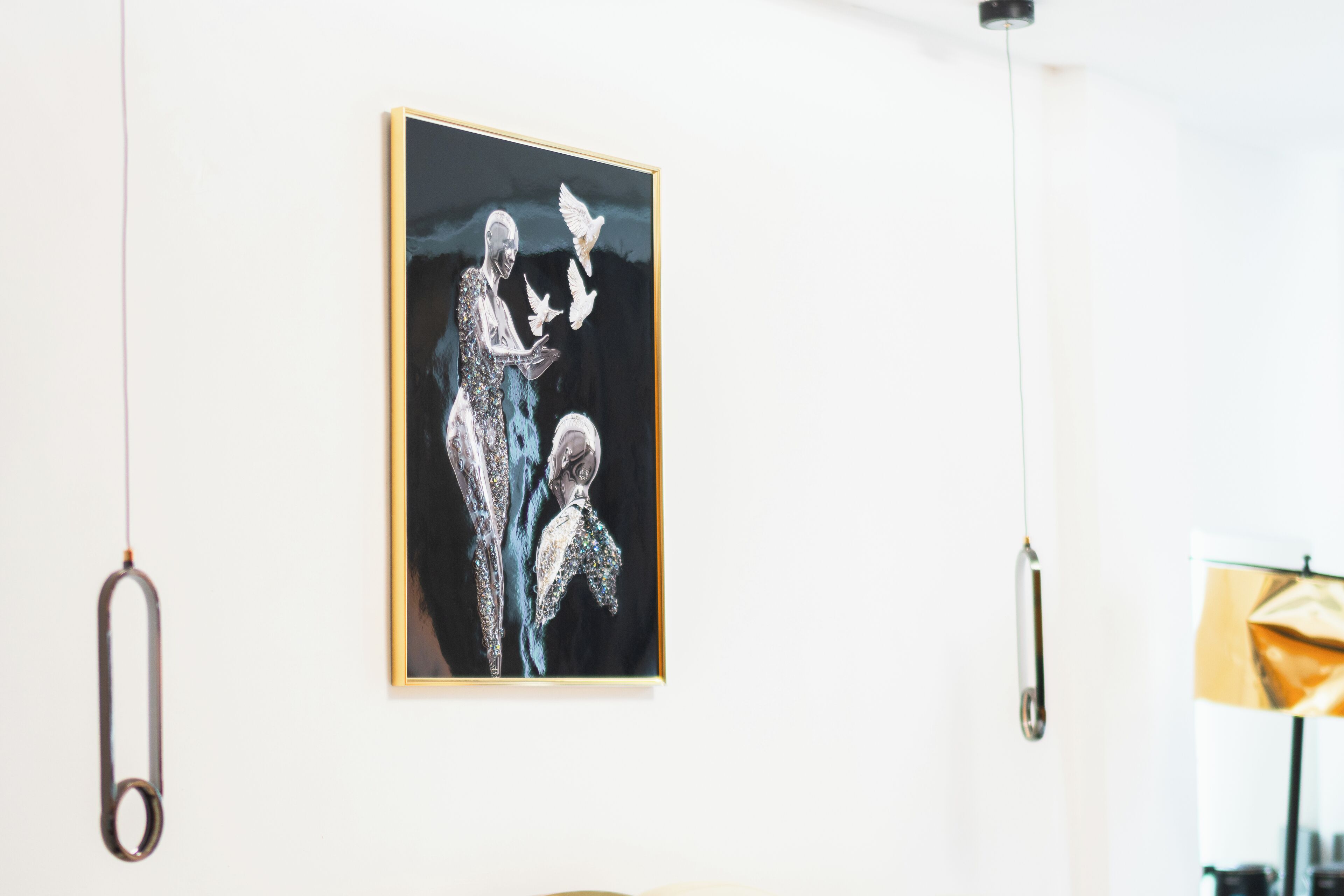 A framed artwork on a white wall, a hanging light fixture, and a partial view of a room with a yellow object.