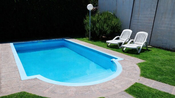 A rectangular swimming pool with a blue interior and a brick border. - Almeria Hotel (San Rafael)