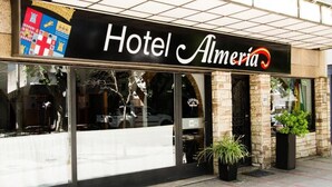 A hotel named "Hotel Almeria" with a large sign above the entrance, large windows, and potted plants outside. - Almeria Hotel (San Rafael)