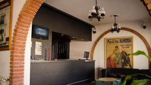 A reception area with a brick archway, a black reception desk, and a poster of Plaza de Toros Almeria. - Almeria Hotel (San Rafael)