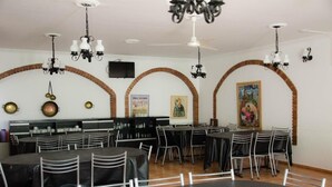 A dining area with round tables and chairs, arched brick walls, and hanging chandeliers. - Almeria Hotel (San Rafael)