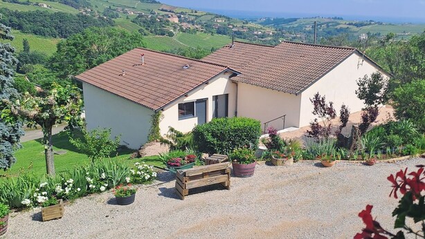A two-story house with a tiled roof, surrounded by a gravel driveway and various potted plants. - Country house located in a charming little village in Southern Burgundy (Chasselas)