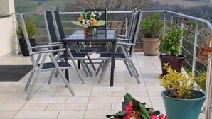 A terrace with a table and chairs, potted plants, and a view of the countryside. - Country house located in a charming little village in Southern Burgundy (Chasselas)