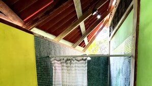 Une petite salle de bain étroite, équipée d’une douche, de toilettes et d’un lavabo.