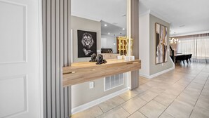 Un interior moderno con un mostrador de recepción de madera, un espejo grande y obras de arte en las paredes.
