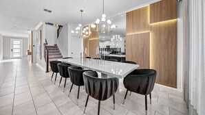 Un comedor moderno con una mesa larga, sillas negras y una araña.