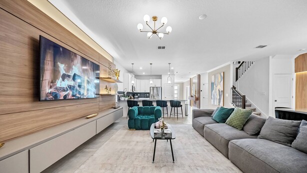 Una sala de estar moderna con un televisor de pantalla plana grande, un sofá color turquesa, un sofá seccional gris y una mesa de centro.