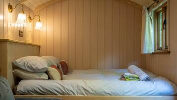 A bedroom with a wooden headboard, a bed with multiple pillows, a bedside table, and wall-mounted lamps.