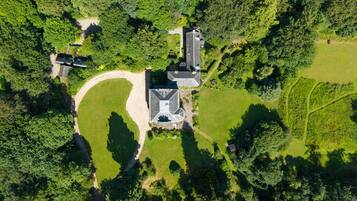 An aerial view of a property with a central building, surrounding green spaces, and a circular driveway.