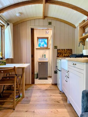 Une cuisine avec des meubles en bois, un four encastré et une fenêtre ornée de vitres à motifs géométriques.