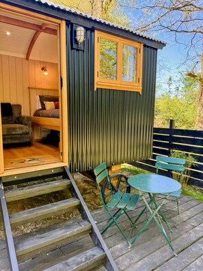 Une cabane confortable avec un lit, une petite table et des chaises à l’extérieur.