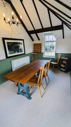 A dining area with a wooden table and chairs, a chandelier, a window with a view, and a radiator. - Scottish Estate Getaway at Powis House Estate (Stirling)