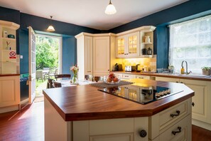 Une cuisine moderne dotée d’un îlot central, de meubles blancs et offrant une vue sur l’extérieur.