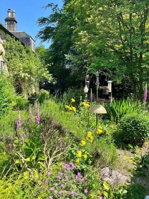 A garden with a variety of plants and flowers, a lamp post, and a building with a chimney in the background. - Scottish Estate Getaway at Powis House Estate (Stirling)
