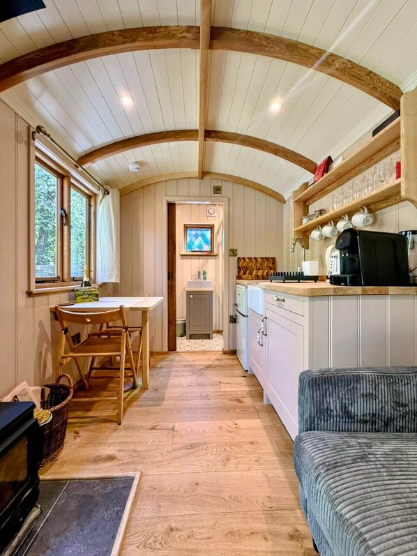 A compact kitchen with wooden beams, a dining area with a table and chairs, and a small kitchenette.