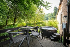 An outdoor seating area with a table and chairs, a hot tub, and a wooden deck.