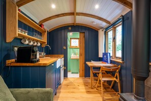 A compact kitchen with a coffee machine, a sink, and a window with a view. - Boutique Shepherd Hut w Garden & Outdoor Bath (Stirling)