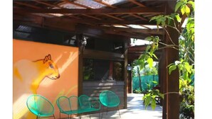 Un espacio de estar al aire libre con un mural de un perro, una pérgola y plantas en macetas.