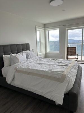 A bedroom with a large bed, a chair, and a view of the outdoors. - Puncak dream 5 minute walking to lake and mushroom and bee farm in progress. (Swanigan lake)
