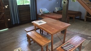 A rustic room with a wooden table and benches, a staircase, and a window with curtains. - Colibri Cabina - Jungle Cabina with Pool Access (Cabuya)