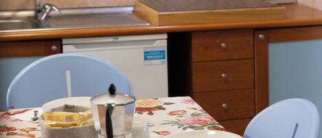 A kitchen with wooden cabinets, a sink, and a dining table set with plates, cups, and a coffee pot.