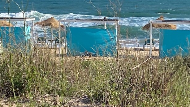 Een strand met een zwembadgedeelte, inclusief ligbedden en parasols.