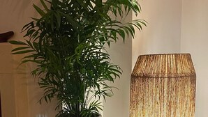 Een potplant op een witte tafel naast een hoge, geribbelde vloerlamp.