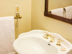 Une salle de bain avec un lavabo blanc, des robinets dorés et un miroir.