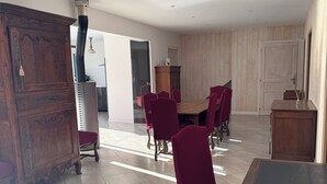 Un vaste espace dédié à la salle à manger, avec une table en bois et des chaises assorties, un buffet en bois, et une cuisine moderne en arrière-plan.